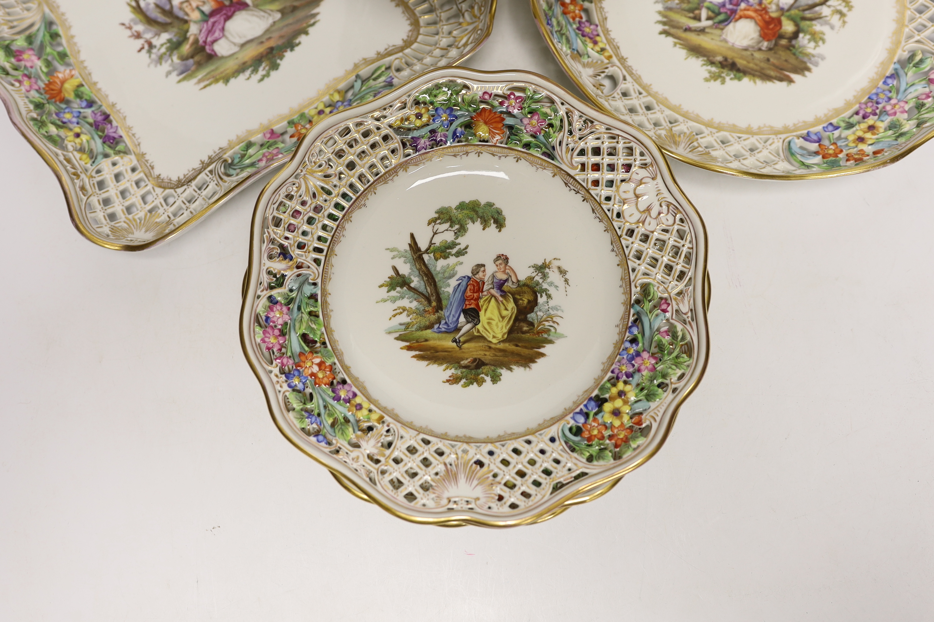 A Dresden Meissen style part dessert set, painted with courting couples in the landscape, consisting of a comport two dishes and four plates, comport 15.5cm high